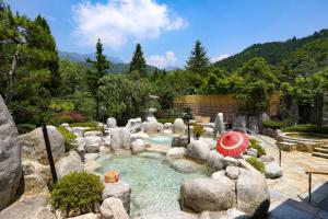 a garden with a pool with rocks and an umbrella at TAOYA Kisoji in Nagiso