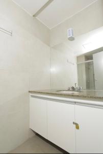 a white bathroom with a sink and a mirror at Apartamento 1009 in Goiânia