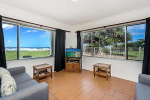 a living room with a couch and a tv and windows at Apartment 4B in Lennox Head