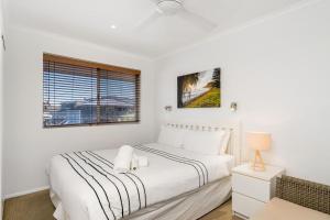 a white bedroom with a bed and a window at Apartment 8T in Lennox Head