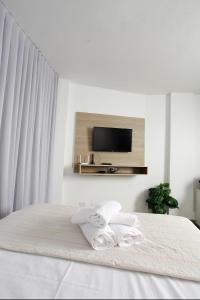 a white bedroom with a bed with two towels at Apartamento 1009 in Goiânia