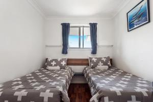 レノックス・ヘッドにあるAbsolute Beachfront Apartments 3Tの窓のある小さな部屋にベッドが2つある