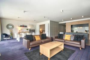 a living room with two couches and a table at Absolute Lake Front Luxury- 2 bedroom apartment in Queenstown