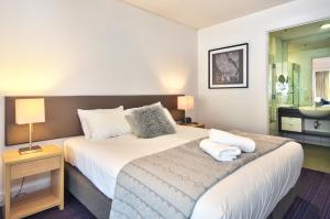 a bedroom with a large bed and a bathroom at Absolute Lake Front Luxury- 2 bedroom apartment in Queenstown
