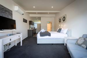 een slaapkamer met een bed en een tv en een bank bij Studio Apartment - 5 Minutes to Hobart CBD - Free Parking - Free WIFI in Sandy Bay