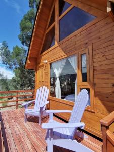 two white chairs sitting on the deck of a cabin at El Ensueño in Villa de Leyva