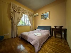 a bedroom with a bed and a chair and a window at Seladah Stay in Kuching