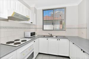 a white kitchen with a stove and a microwave at Ocean Palms Unit 1 in The Entrance