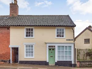 a house with a green door and a brick building at The Yellow Cottage On The Hill in Framlingham