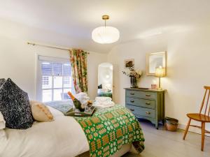 a bedroom with a bed and a dresser and a window at The Yellow Cottage On The Hill in Framlingham