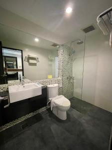 y baño con aseo, lavabo y ducha. en New World Express Motel en Bintulu