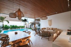 een woonkamer met een tafel en stoelen en een zwembad bij Amaka Villas in Uluwatu