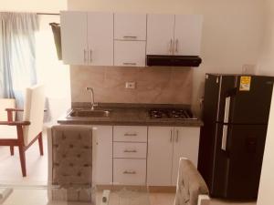 Una cocina con gabinetes blancos y un refrigerador negro. en Cabañas Paulamar - Apto 2 - Tolu, en La Gloria