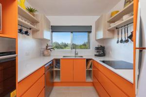eine orangefarbene und weiße Küche mit einem Waschbecken und einem Fenster in der Unterkunft No 1 Seaspray in Forster