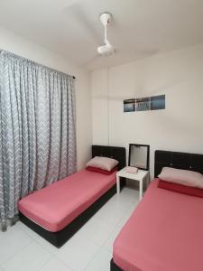 una habitación con 2 camas y un ordenador portátil en una mesa en Ijanina Homestay en Bandar Puncak Alam