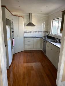 Il comprend une cuisine avec des placards blancs et du parquet. dans l'établissement Tamaterau Seaview House in Whangarei, à Whangarei