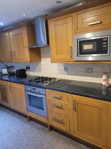 a kitchen with wooden cabinets and a blue stove top oven at No 6 Decent Home (Cozy double bedroom) in Ashton under Lyne