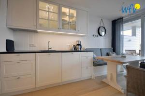 a kitchen with white cabinets and a table in a room at Achterhus - Ferienwohnung Inseltraum in Juist