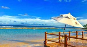 - un parasol blanc assis sur une plage près de l'eau dans l'établissement EKOARA RESIDENCE BEIRA MAR Muro alto, à Porto de Galinhas