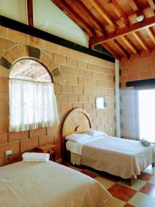a bedroom with two beds and a brick wall at Casa Ikal en San Juan del Rio con Alberca y Temazcal. in San Juan del Río