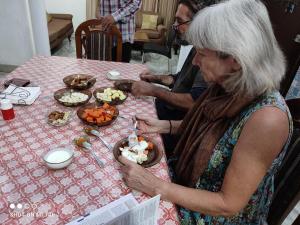 a woman sitting at a table with a plate of food at Aradhanas Home Stay Near Taj Mahal in Agra
