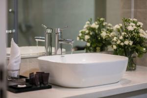 - un lavabo blanc assis sur un comptoir de salle de bains orné de fleurs dans l'établissement Flora Centre Hotel & Spa, à Hanoï