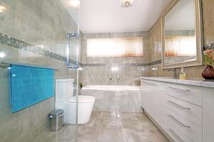 a bathroom with a tub and a toilet and a sink at Melbourne Luxury Villa at Doncaster in Nunawading