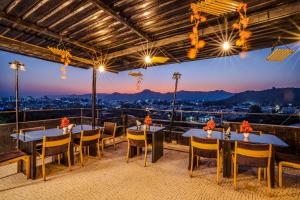 a restaurant with tables and chairs and a view of the city at Tripli Udaipur in Udaipur