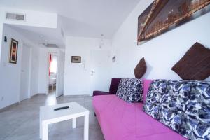 a living room with a pink couch and a table at Yam Suf By Sun and View in Eilat