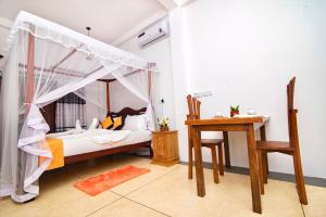 ein Schlafzimmer mit Himmelbett und Schreibtisch in der Unterkunft VILLA RAY WHITE Unawatuna in Unawatuna + 1 Foto