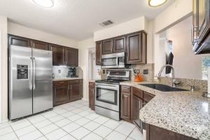 a kitchen with wooden cabinets and stainless steel appliances at 3B Villa w Pool, BBQ, Firepit, Yard Games, Gym in San Antonio