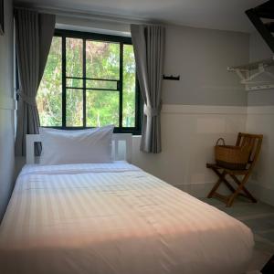 a bedroom with a bed with a window and a chair at Island House Rentals 26 in Ko Samed