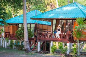 a woman sitting on a deck of a house at Libong Beach Resort in Ko Libong