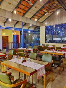 un restaurante con mesas y sillas de madera y ventanas en Willow Resorts, en Ambalavayal