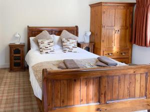um quarto com uma grande cama de madeira e armários de madeira em Sluice Keepers Cottage em Skelbo