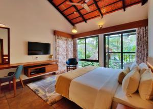 Dormitorio con cama, escritorio y TV en Willow Resorts, en Ambalavayal