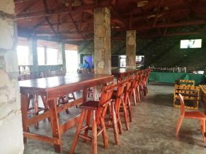 uma longa mesa de madeira e cadeiras num quarto em Murchison Backpackers em Masindi