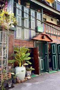 a building with green doors and plants in front of it at Ma Guesthouse Chiang Mai in Chiang Mai