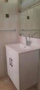 a white bathroom with a sink and a mirror at har nof apartment in Jerusalem