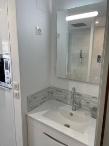 a white bathroom with a sink and a mirror at Golden Paradise 007 Port Nat in Cap d'Agde