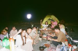 un grupo de personas sentadas alrededor de una fiesta en la playa en Lazy House en Hualien