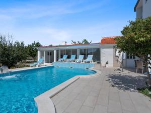 a swimming pool with chairs and a house at Beautiful Holiday Home in Neoric in Neorić