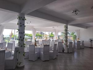 une salle de banquet avec des tables blanches et des chaises blanches dans l'établissement Aux 2 Métis, à Toliara