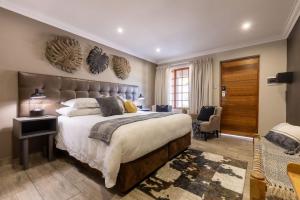 a large bedroom with a large bed and a chair at Lowveld Living Guesthouse in Nelspruit