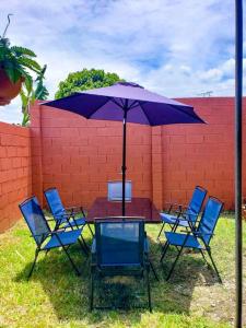 einen Tisch mit blauen Stühlen und einem Sonnenschirm in der Unterkunft Jasper House en Ciudad Real Santa Ana in Santa Ana
