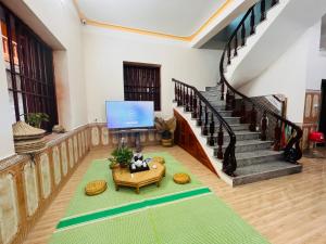 a living room with a staircase and a tv at Homestay Bản Giốc- Tay's Traditional Village in Cao Bằng