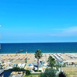 Une plage avec beaucoup de gens et l'océan dans l'établissement Hotel Blue Moon, à Rimini