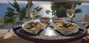 a table with bowls of food and glasses of wine at Apartmán Alex beach s nádherným panoramatickým výhledem na moře in Sveti Vlas