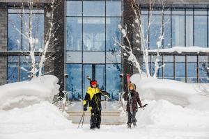 two people standing in the snow in front of a building at Park Hyatt Niseko Hanazono in Kutchan