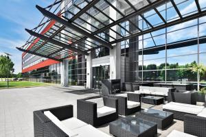 een patio met stoelen en tafels in een gebouw bij Novina Hotel Herzogenaurach Herzo-Base in Herzogenaurach